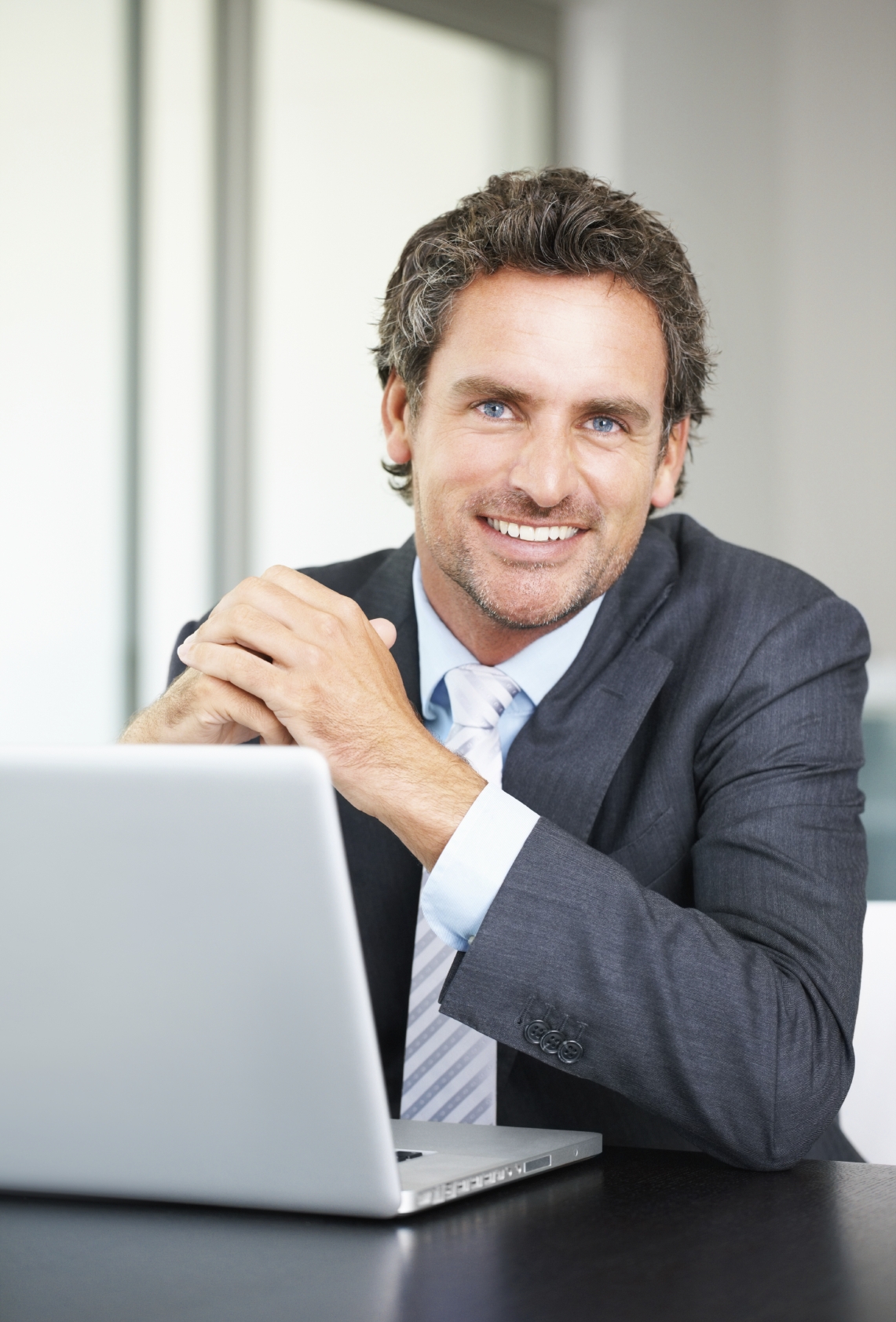 Portrait of business man using laptop and giving you a warm smile - KGR ...